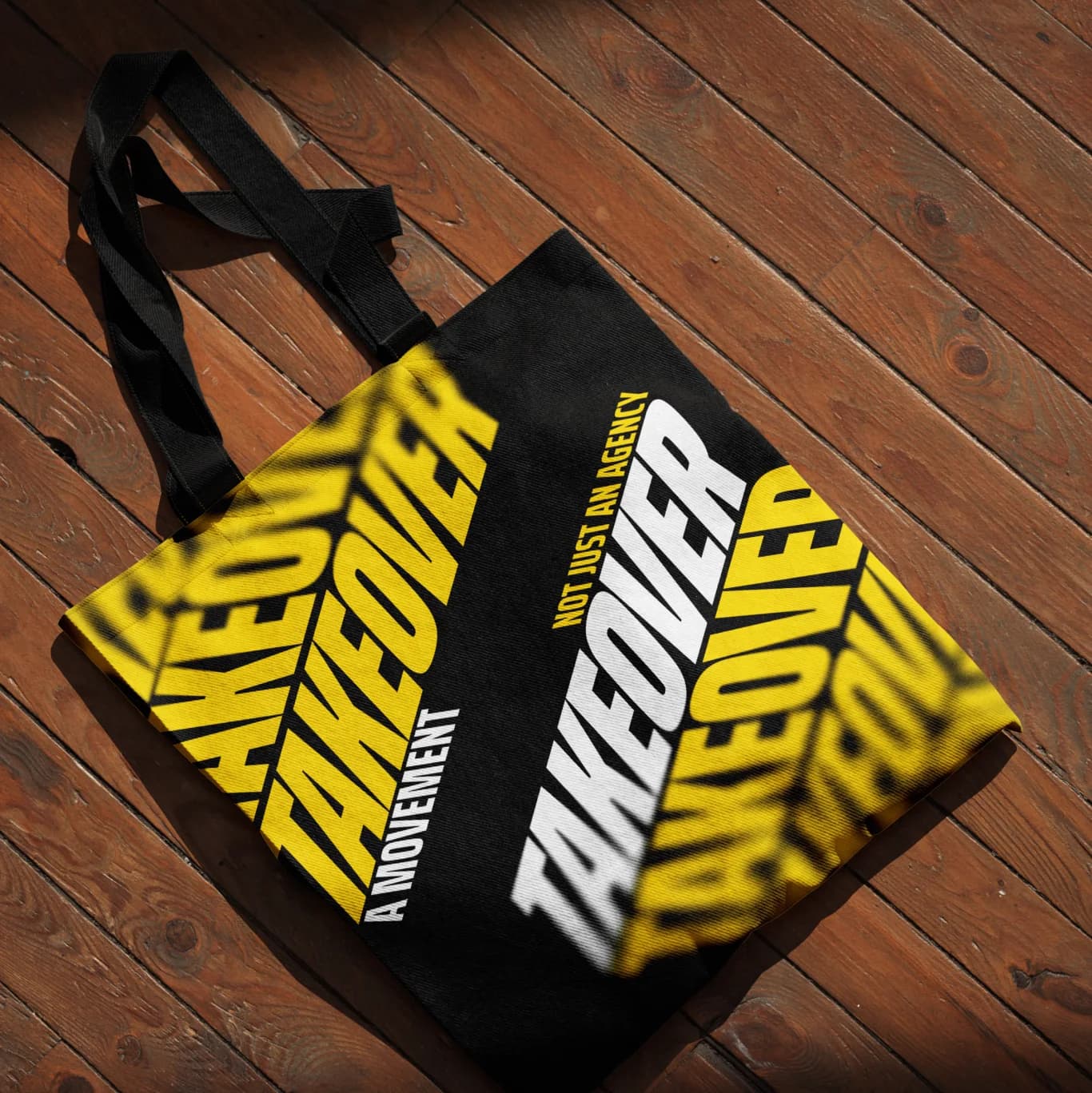 Black Takeover tote bag on a wooden floor
