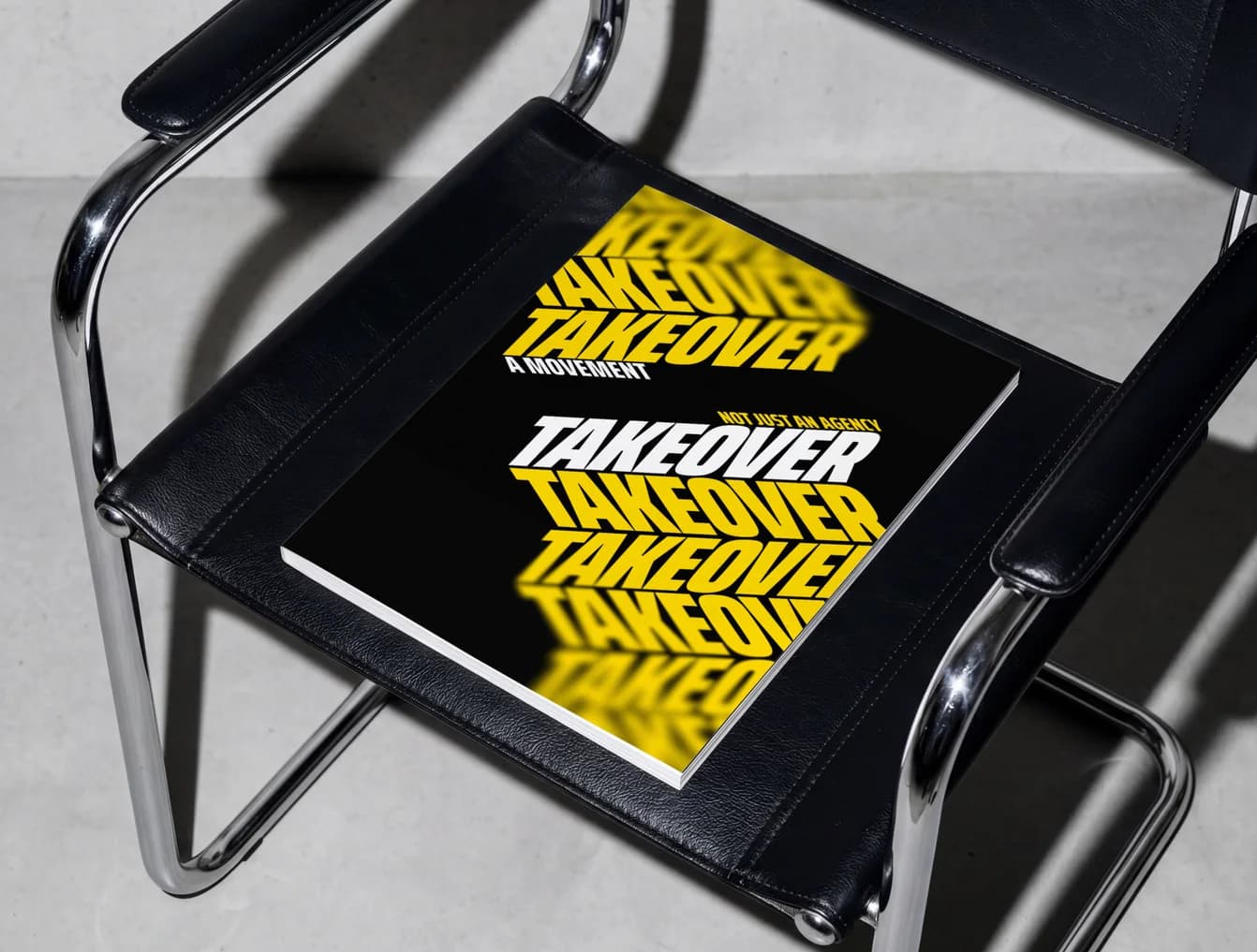 Takeover book on a black leather chair, the name stacked in yellow
