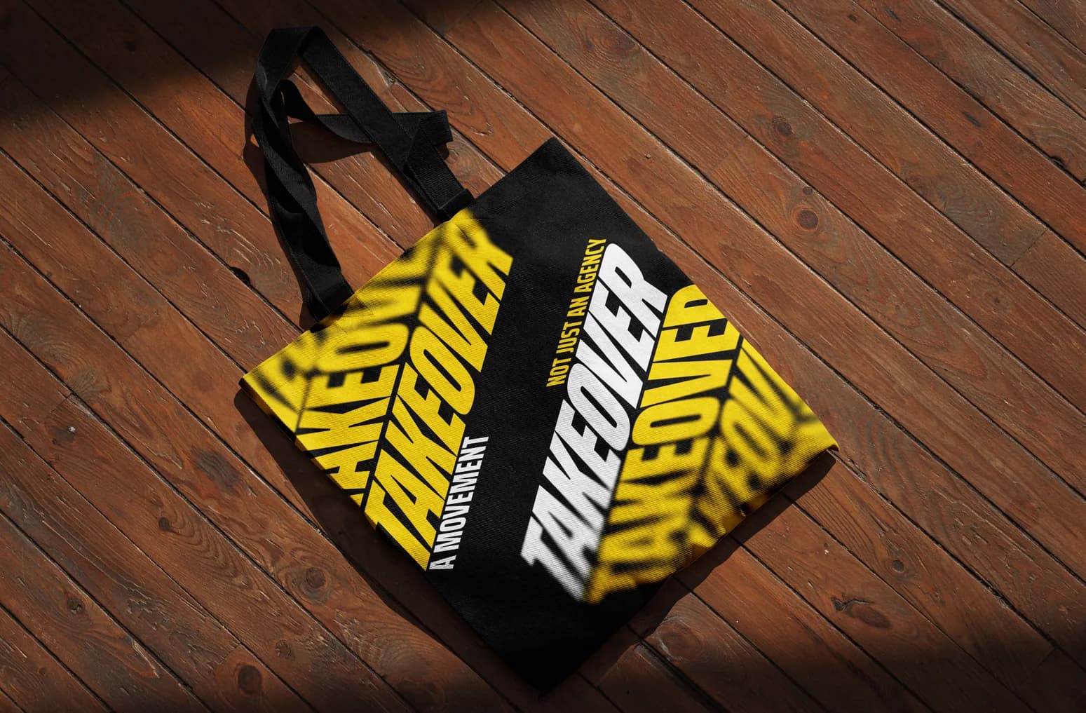 Black Takeover tote bag on a wooden floor