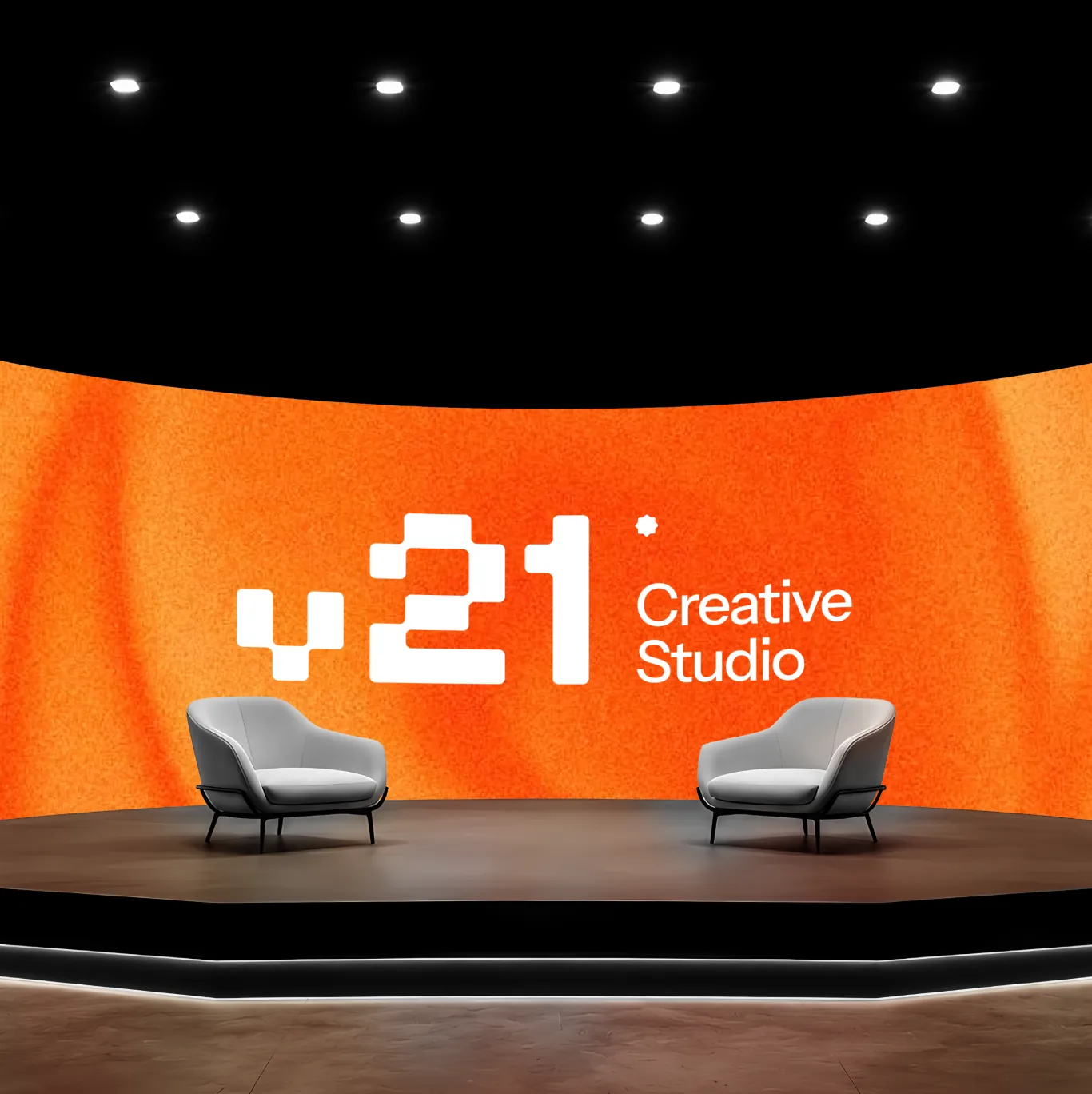 V21 Creative Studio on a curved orange stage screen, two armchairs in front